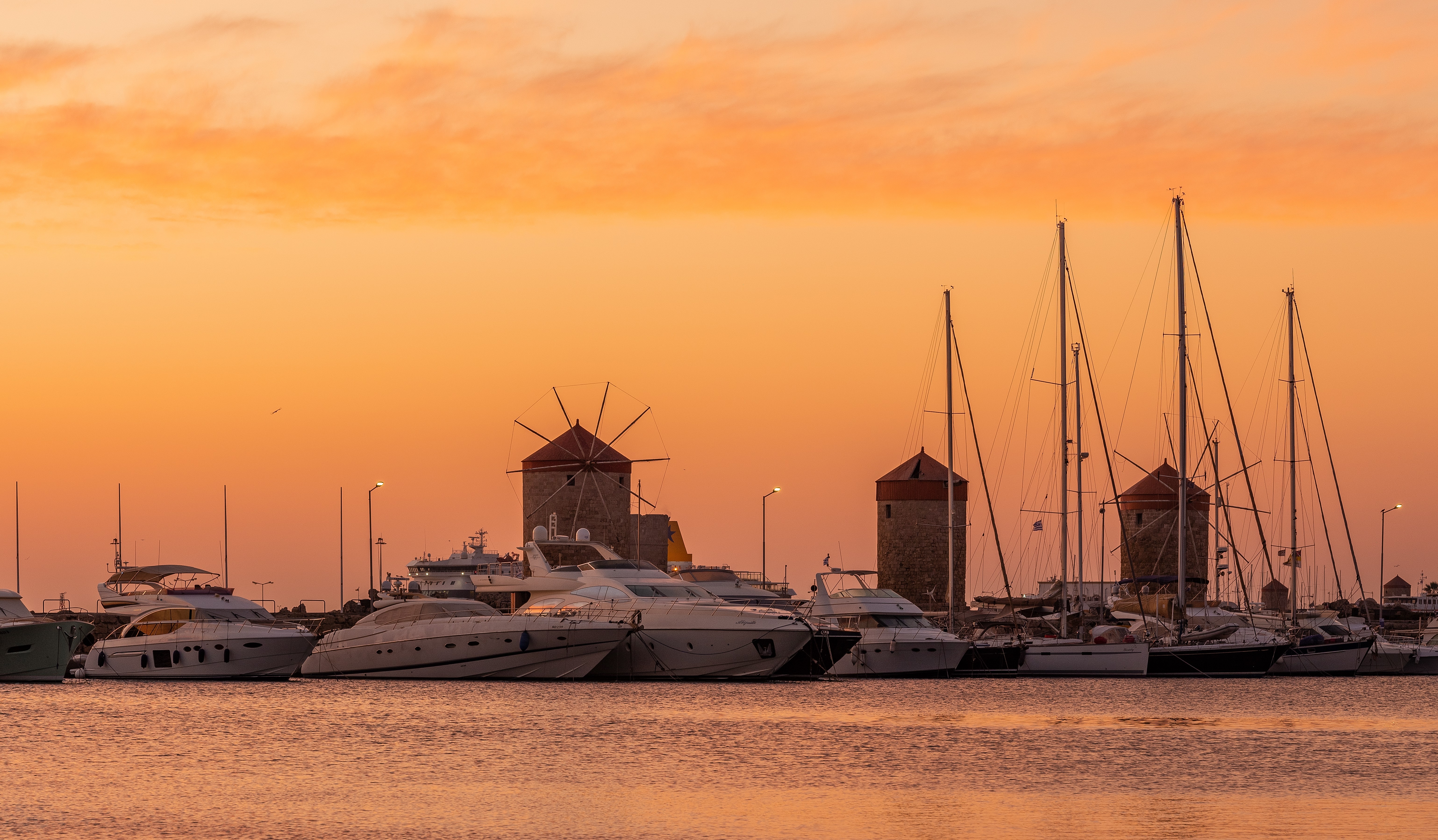 Panorama miasta Rodos z widokiem na historyczne mury i port Mandraki, oświetlona słońcem wyspy.