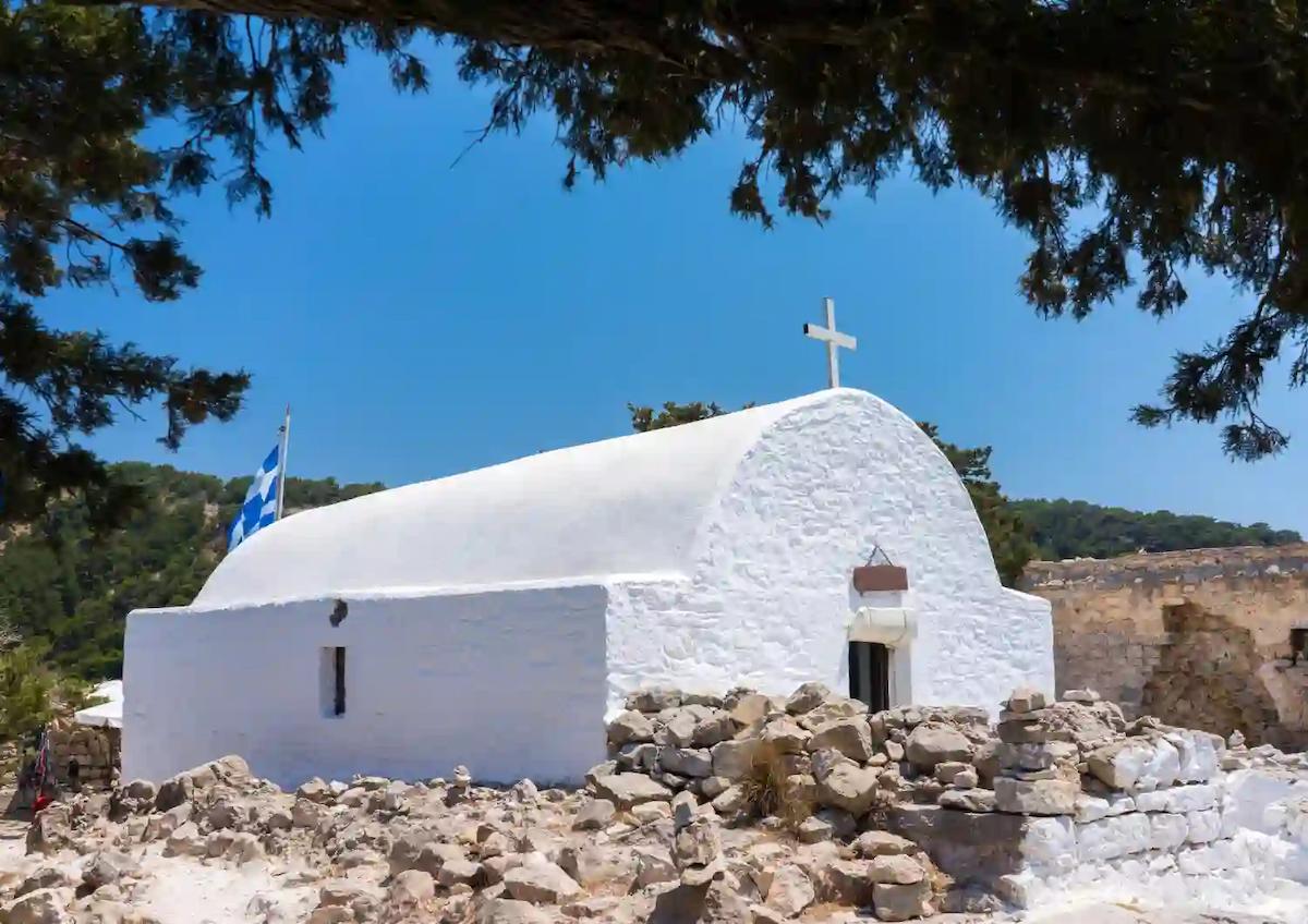Biała kaplica Świętego Pantaleona stojąca pośród kamiennych ruin zamku Monolithos na Rodos.